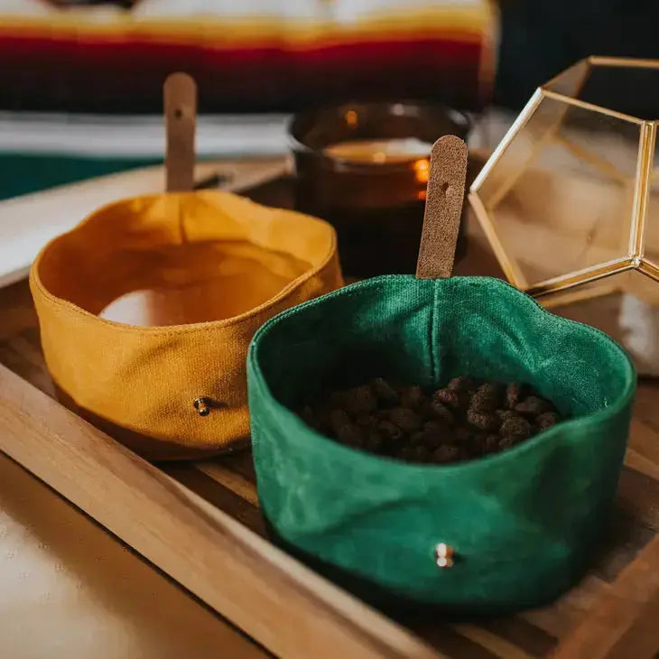 Two waxed canvas dog water bowls on a wooden tray