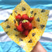 Yellow beeswax wrap with strawberries on a blue and white striped background