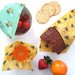 Beeswax wraps being used to wrap food items on a white surface