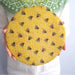 Round yellow object with bee and honeycomb pattern held by a person