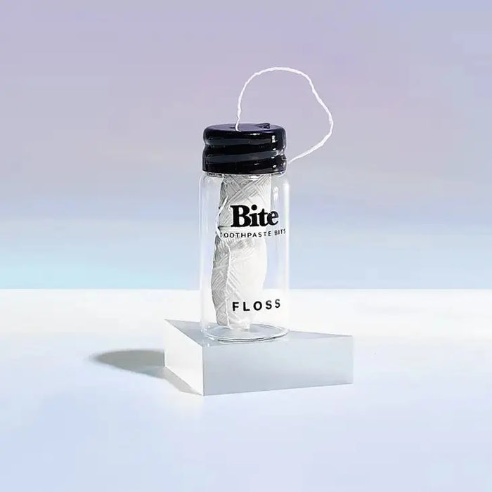 Clear container with black lid labeled 'Bite' on a white platform with a light blue gradient background