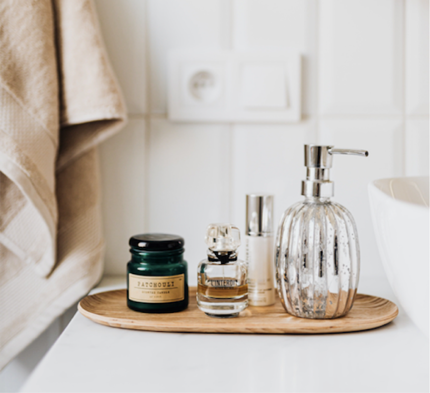 A bathroom counter featuring a soap dispenser, a neatly folded towel, and an elegant bottle of perfume.