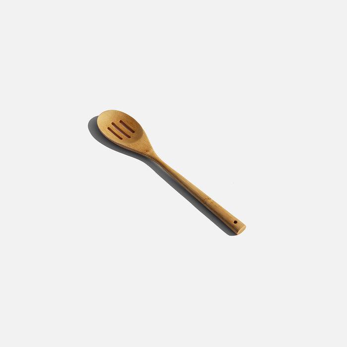 A wooden spoon resting on a clean white surface, showcasing its natural texture and design for cooking purposes.