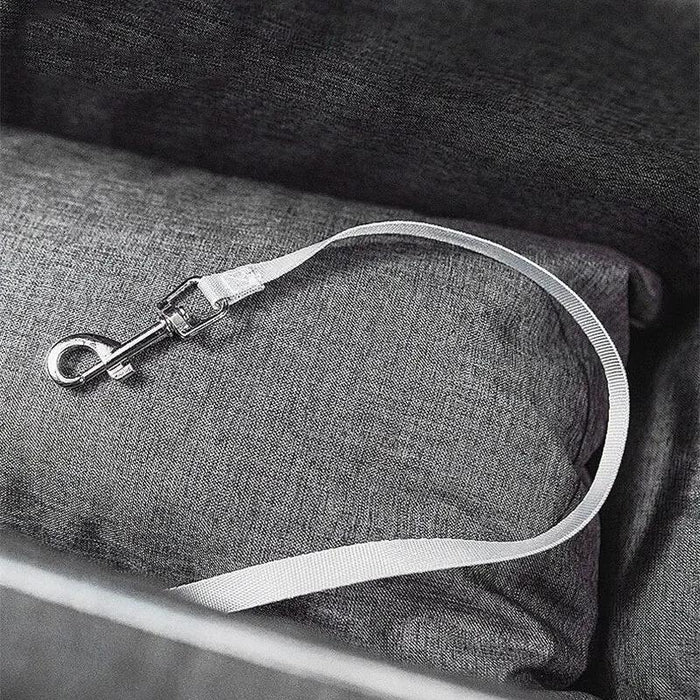 White dog leash with metal clip on a gray fabric surface