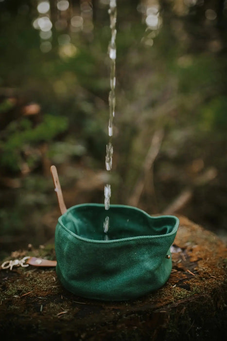 Green woven basket with water flowing into it against a natural background