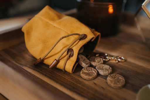 Yellow drawstring pouch with coffee beans on a wooden surface