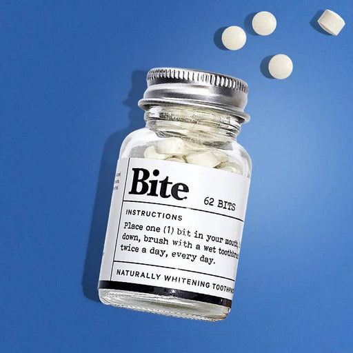 Bottle of 'Bite' toothpaste with tablets on a blue background