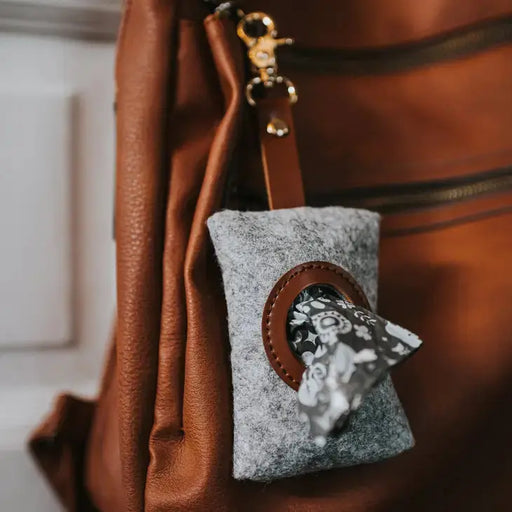 Gray pouch with floral design attached to a brown leather bag