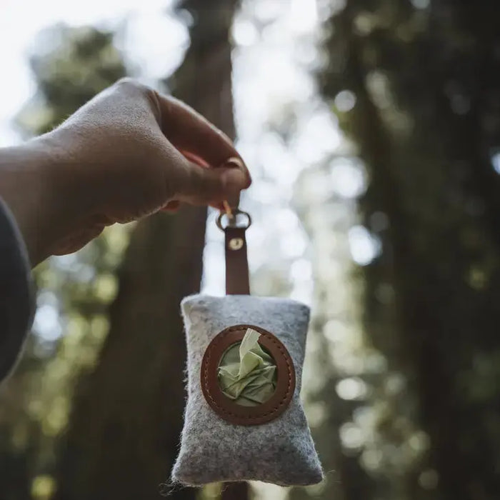 Felted pouch with a leaf design held by a hand against a blurred natural background