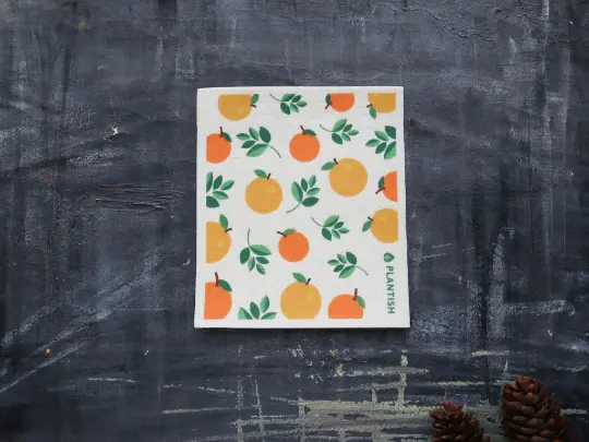 A Swedish sponge cloth with orange and green pattern on a dark textured surface