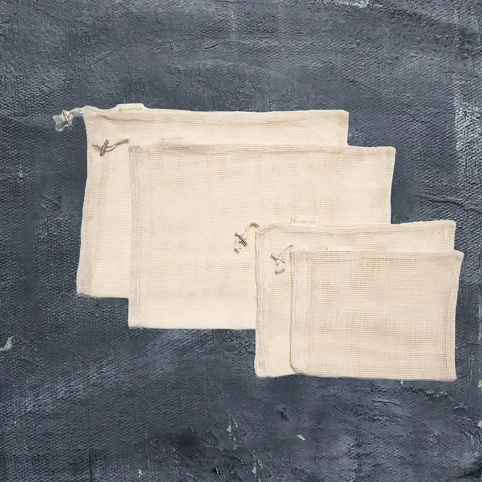 Three beige drawstring bags on a dark textured background