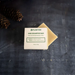 Plantish dog shampoo bar on a dark textured surface with pine cones.