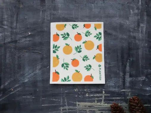 Plantish sponge cloth with orange and green pattern on a dark textured surface