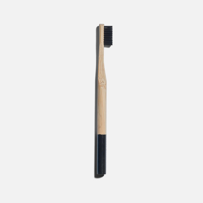 Bamboo toothbrush with black bristles on a white background